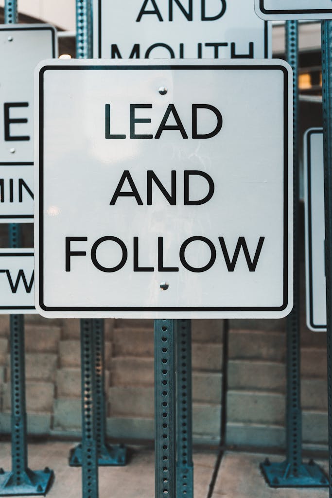 Photo of urban signage displaying 'Lead and Follow', emphasizing guidance and navigation.